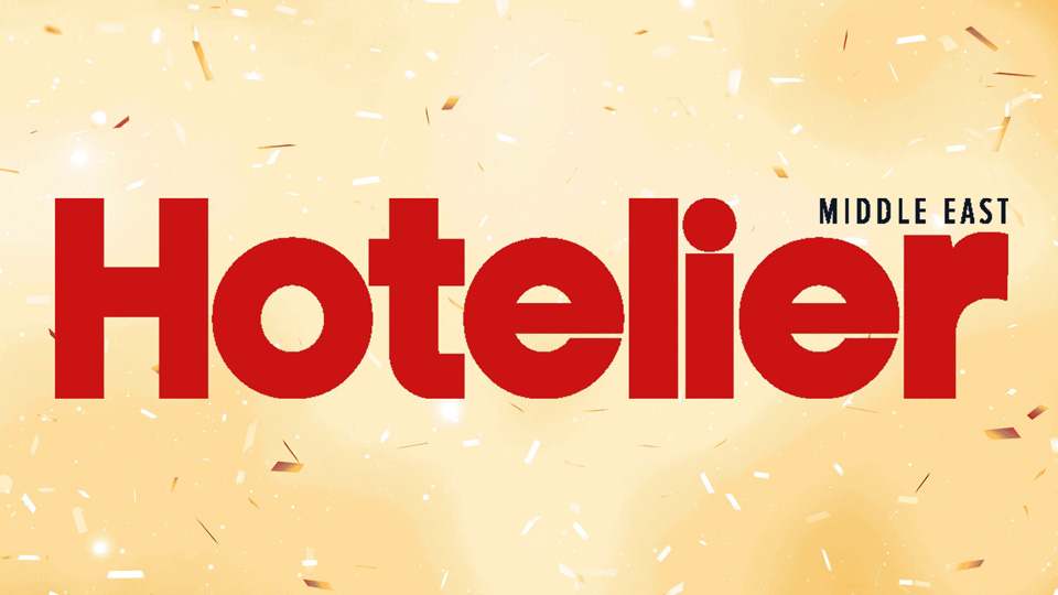 Logo for the online publication Hotelier Middle East, cream background with Hotelier Text in Red