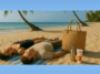 A couple lying on the beach, with palm trees in the distanc. Next to them is a woven straw bag and some Human Nature Sunscreen