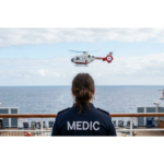 Photo of a medic in a blue uniform on the deck of a cruise ship, looking at a medic helicopter getting ready to land for a medical emergency on a cruise ship